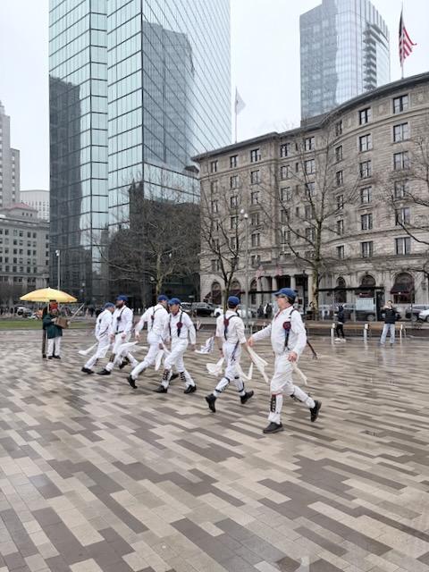 Newtowne Morris performing Fieldtown Dearest Dickie on Copley Plaza across from 200 Clarendon Street, two lines of dancers in whites, suspenders, and blue caps passing each other across the set.